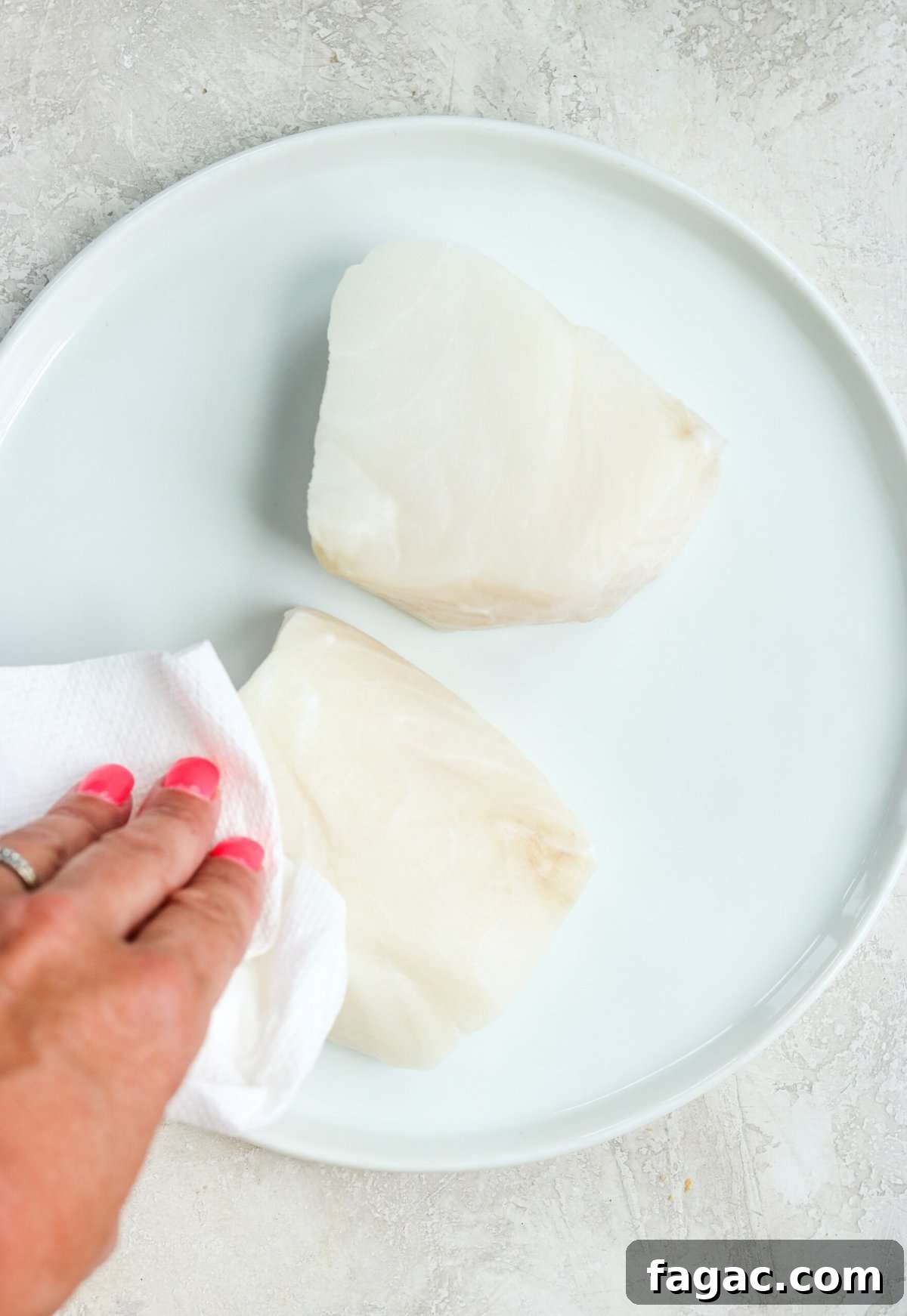 Blotting moisture from sea bass fillet with paper towel