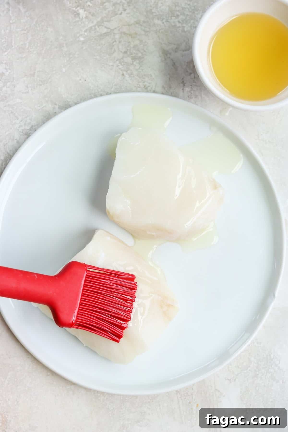 a red brush brushing butter onto sea bass filets