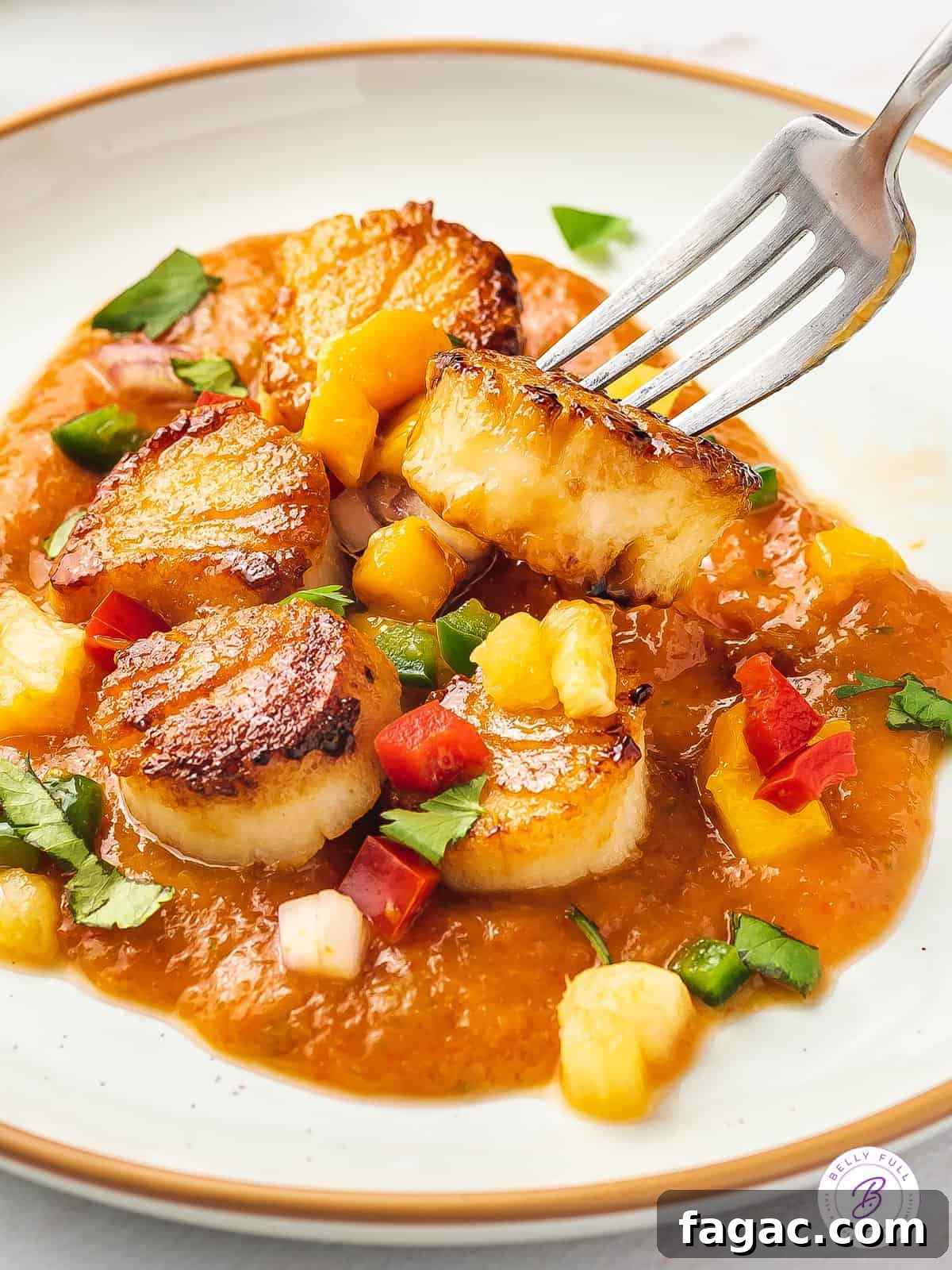 Seared Scallops with Fruit Salsa may look fancy - but it's actually so easy to make! Ready in under 30 minutes! A fork stabbing a scallop in fruit sauce
