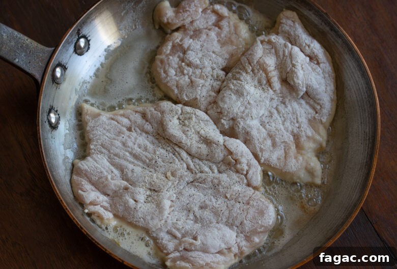 Floured chicken cutlets placed in a skillet