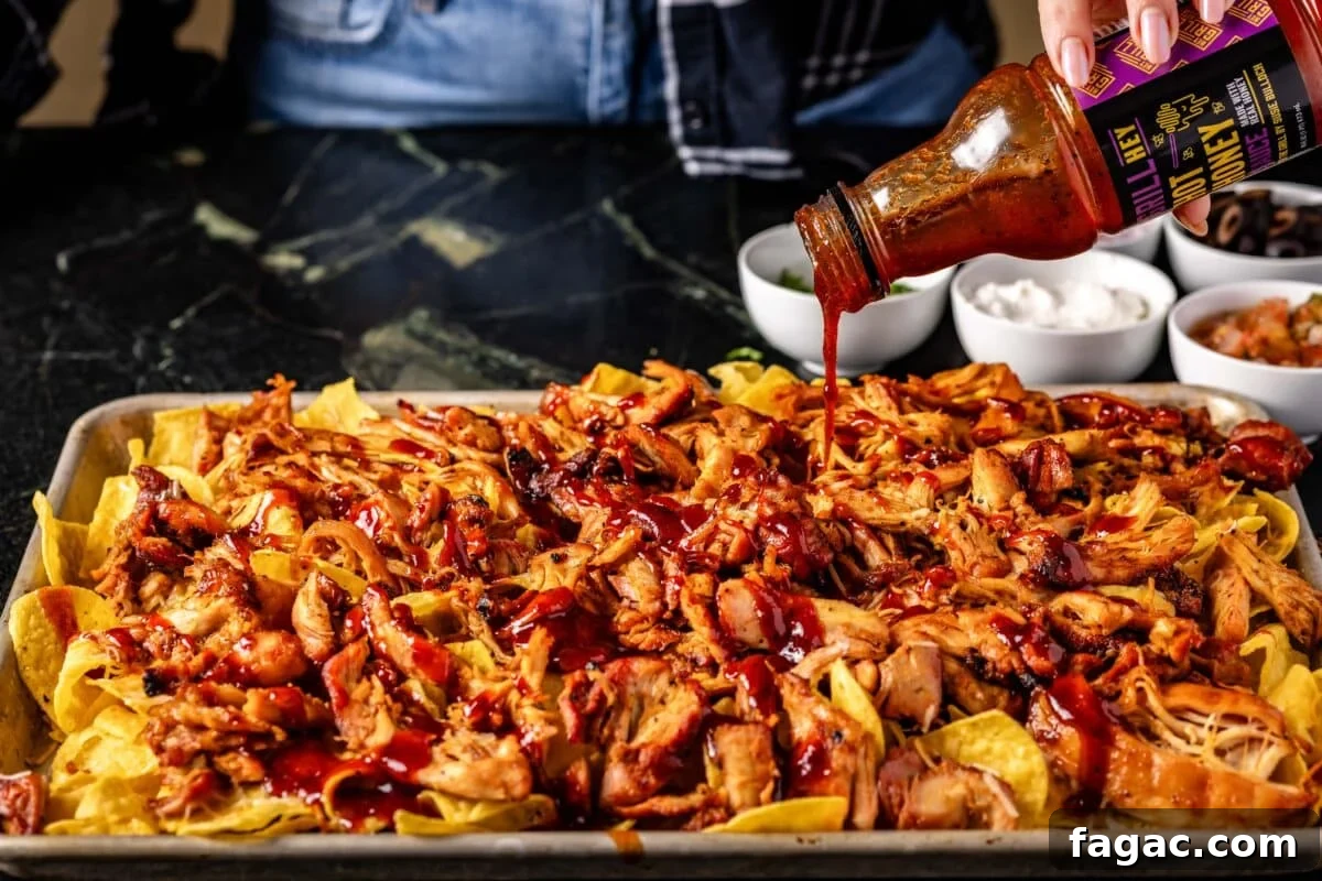 Spicy Honey BBQ Sauce Recipes for Grilling and Glazing 3 A baking sheet of nachos being drizzled with BBQ sauce.