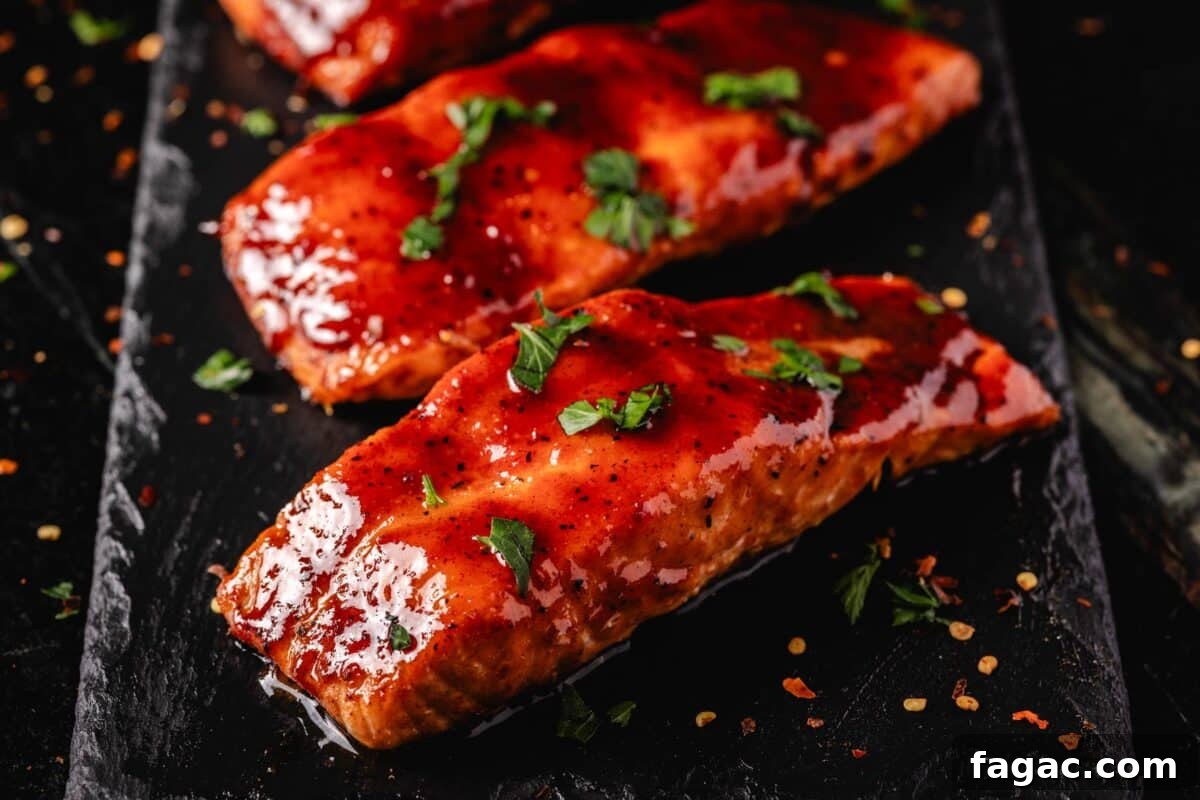 Spicy Honey BBQ Sauce Recipes for Grilling and Glazing 4 Hot Honey glazed salmon fillets on a black platter sprinkled with sliced green onion.
