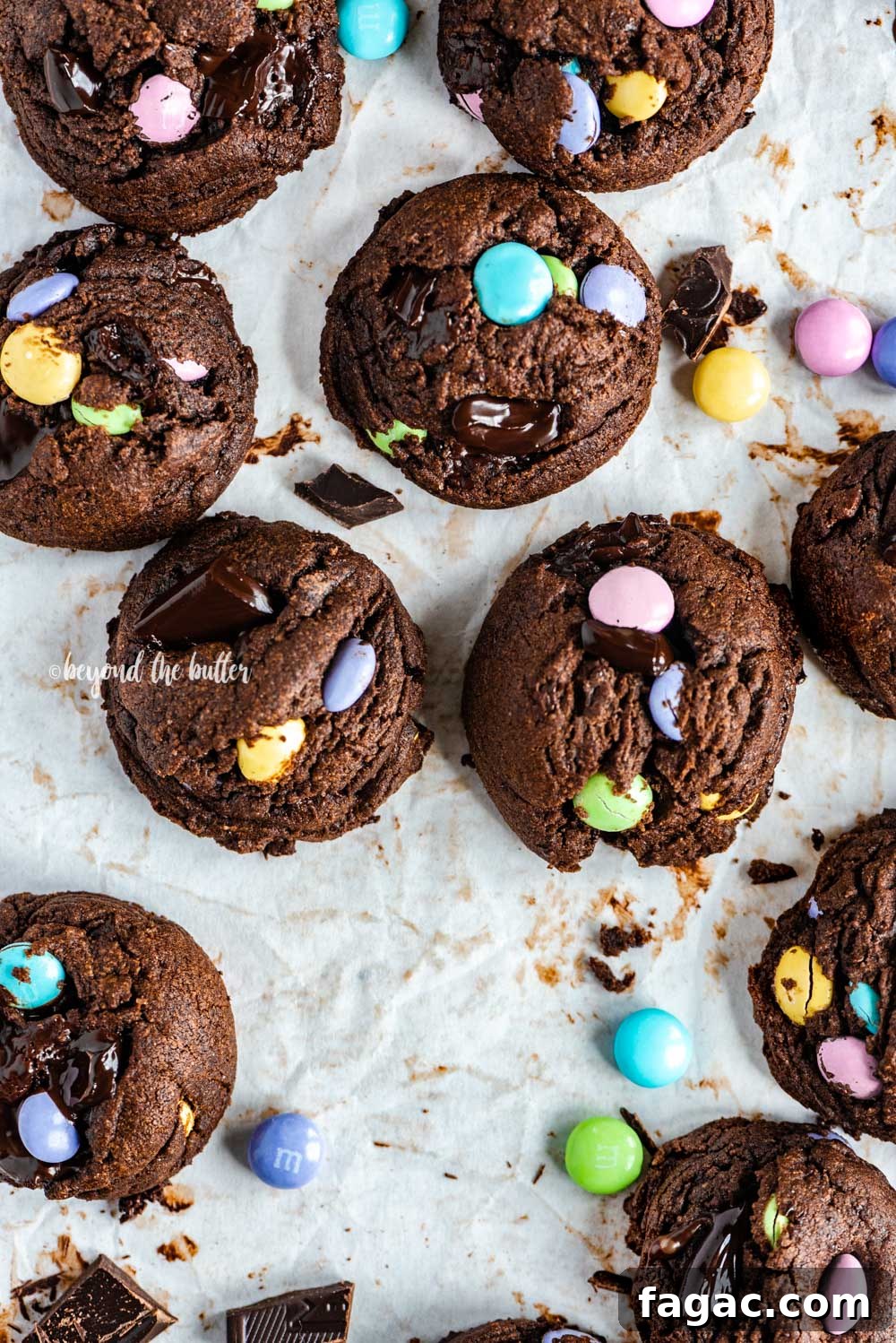 Overhead image of just baked double chocolate chunk m&m cookies on a parchment lined baking sheet | All Images © Beyond the Butter™