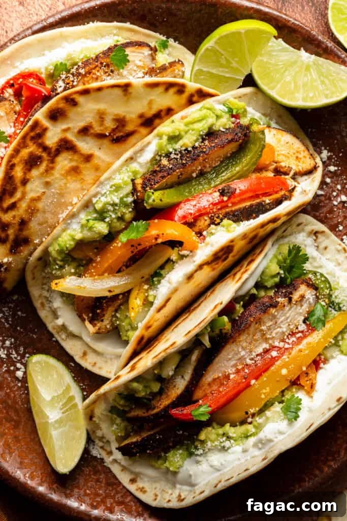 Weeknight Sheet Pan Chicken Fajitas Recipe for Quick Dinners 3 A close-up on three assembled chicken fajitas on a plate, surrounded by lime wedges.
