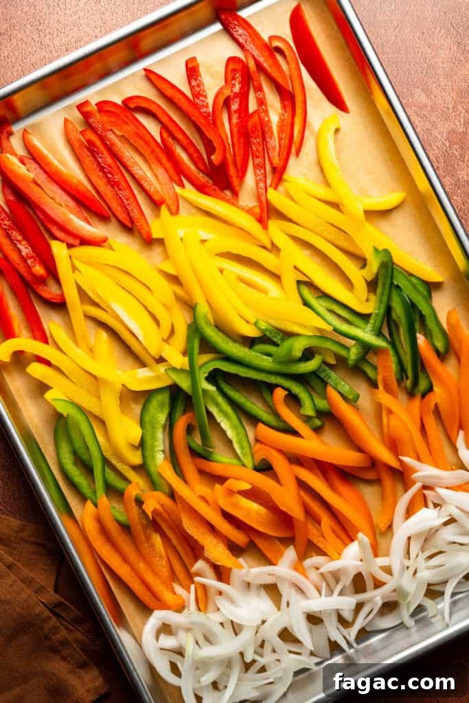 Weeknight Sheet Pan Chicken Fajitas Recipe for Quick Dinners 5 A sheet pan with rows of colorful bell pepper slices and onion slices.