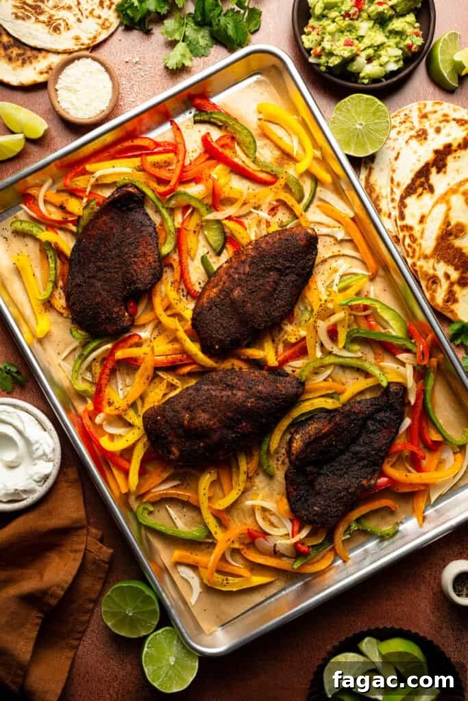 Weeknight Sheet Pan Chicken Fajitas Recipe for Quick Dinners 9 A sheet pan of the chicken breasts laying on top of the roasted pepper slices and onion slices.