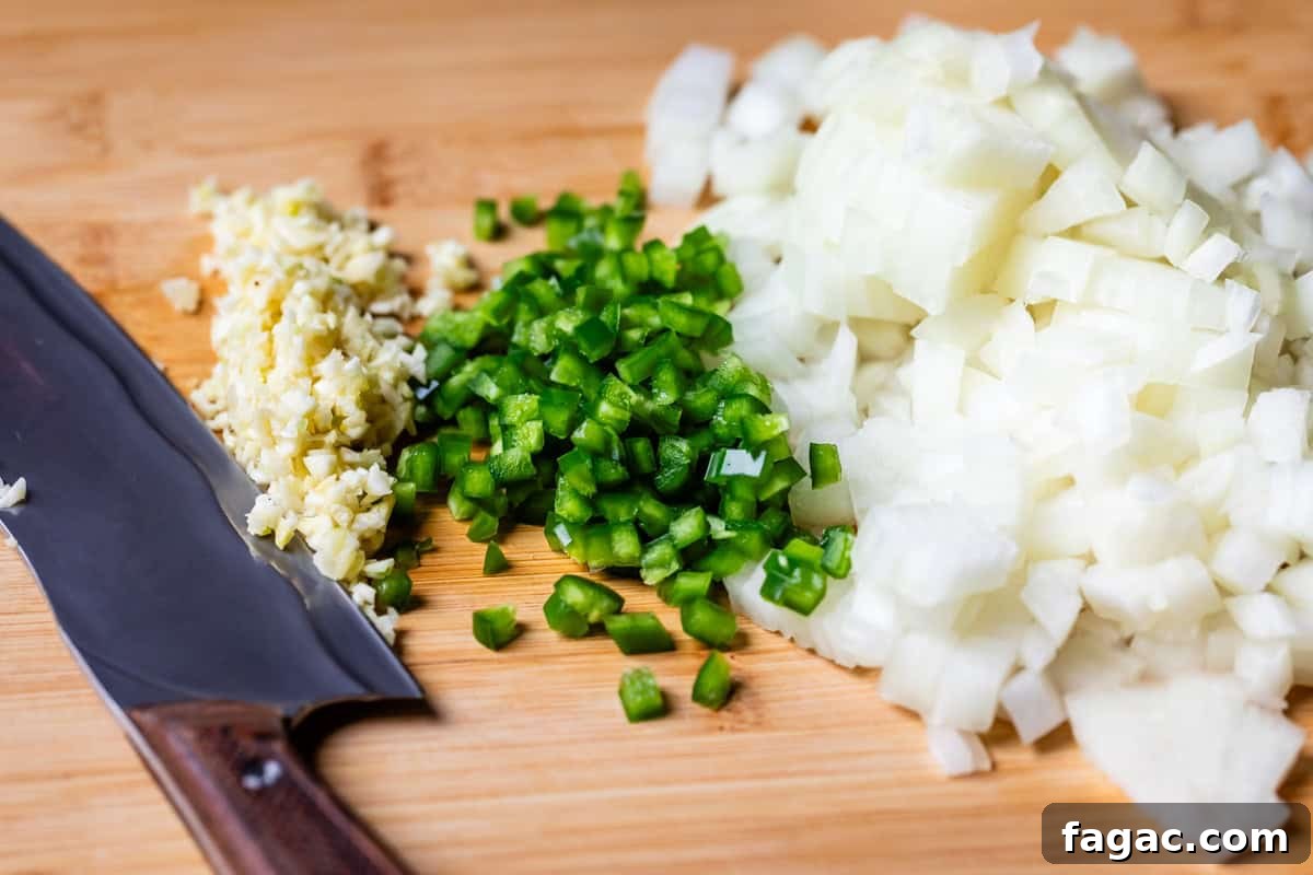 Quick Chicken Tortilla Soup Recipe for Cozy Weeknight Meals 10 diced onion, jalapeno, and garlic on a wooden cutting board.