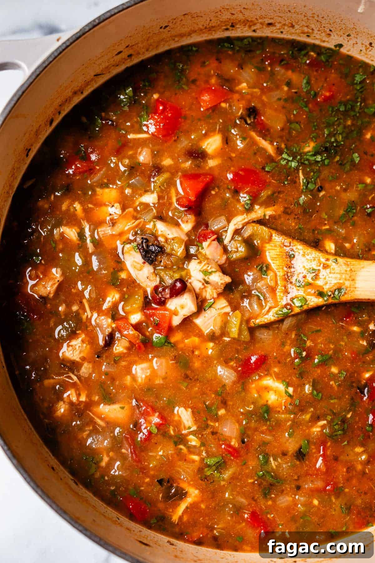 Quick Chicken Tortilla Soup Recipe for Cozy Weeknight Meals 17 looking down into a finished pot of chicken tortilla soup with a wooden spoon in it.