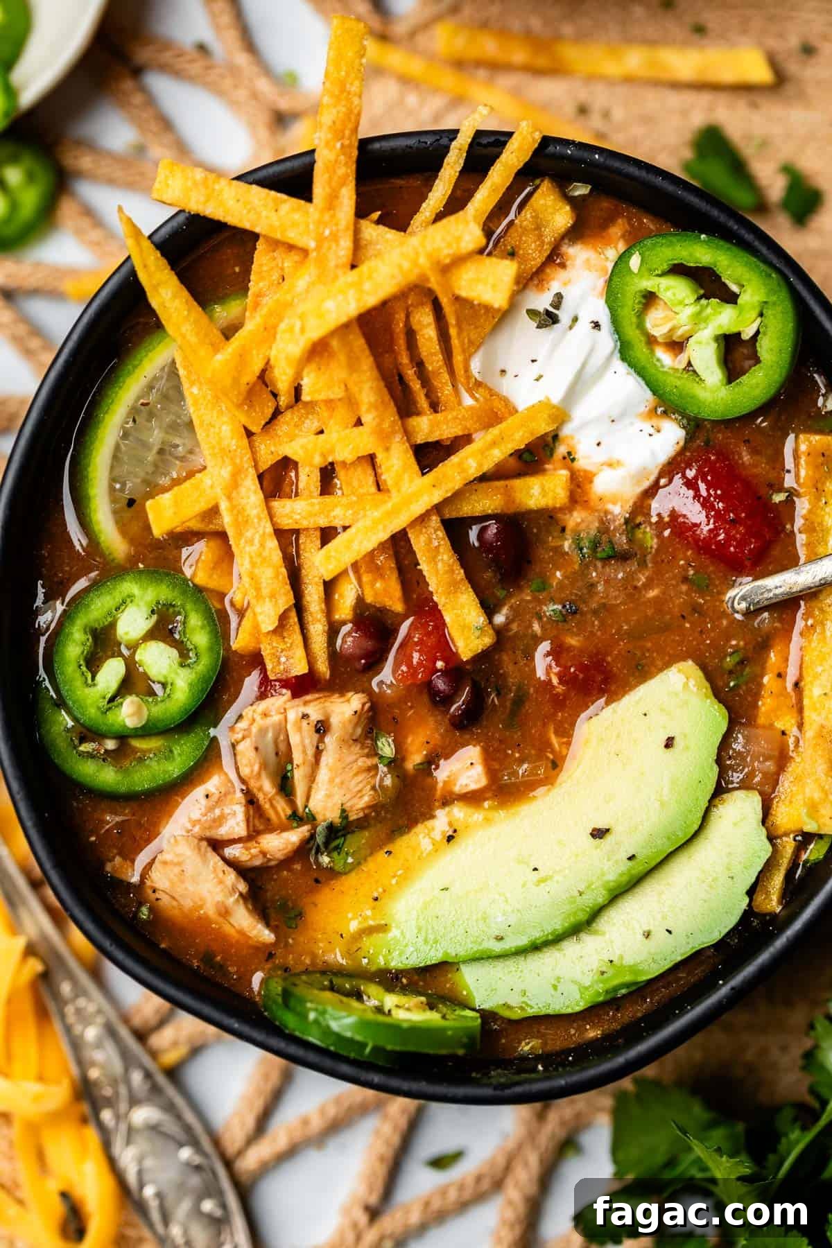 Quick Chicken Tortilla Soup Recipe for Cozy Weeknight Meals 18 bowl of soup with fried tortilla strips, avocado, and jalapeno.