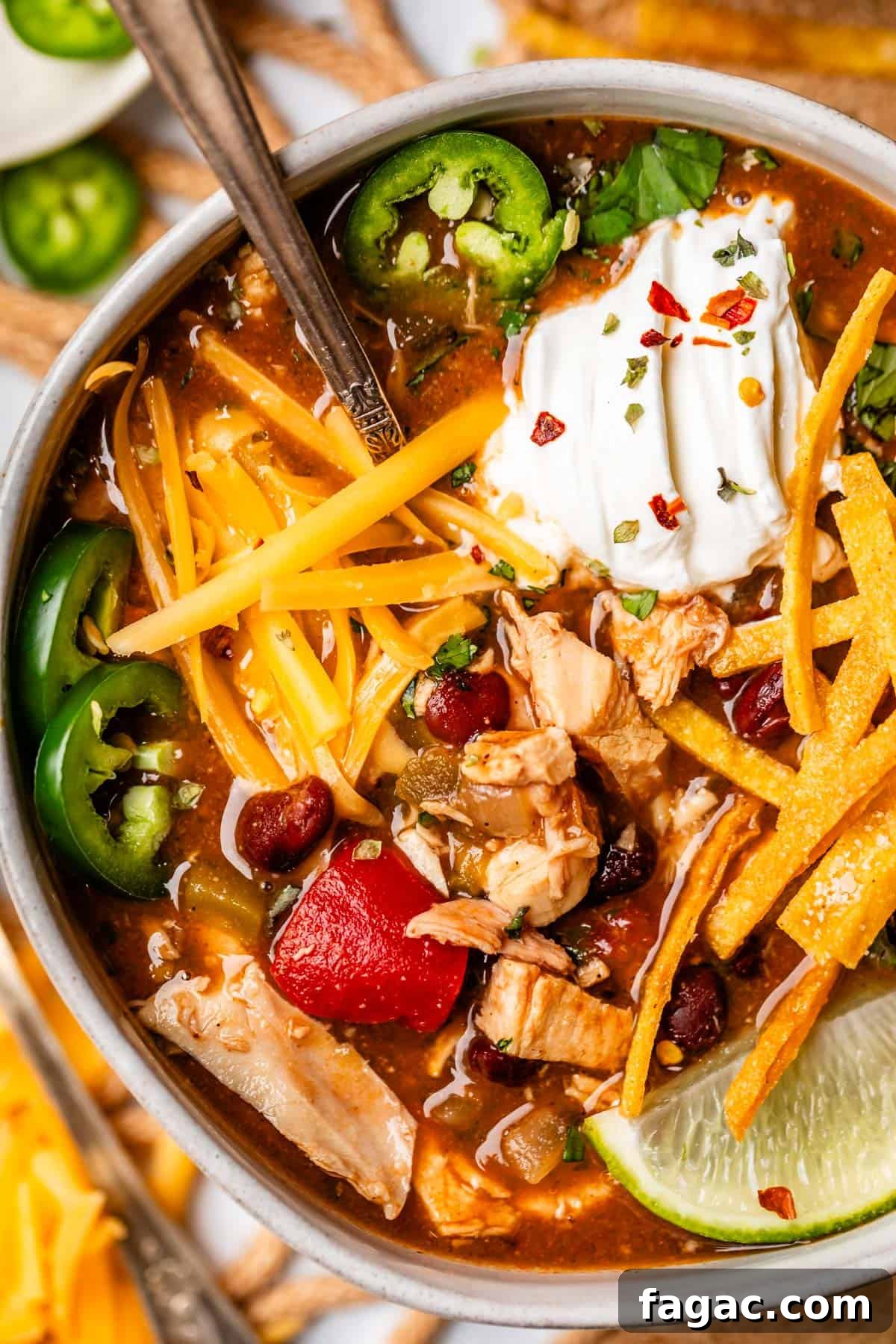 Quick Chicken Tortilla Soup Recipe for Cozy Weeknight Meals 24 bowl with chicken tortilla soup topped with cheese, sour cream, fried tortilla strips, and more.