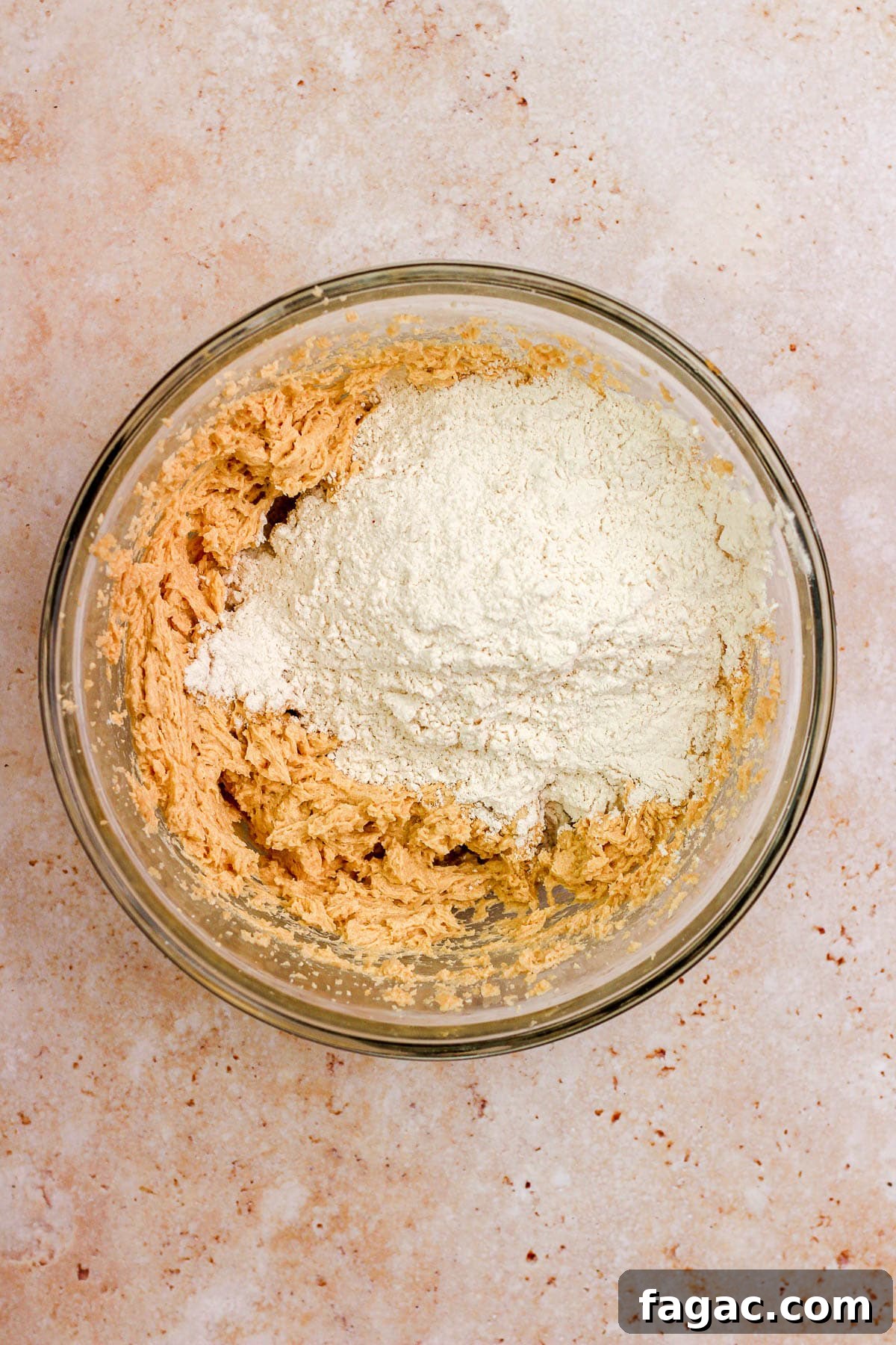 A glass bowl filled with sugar cookie dough and flour.