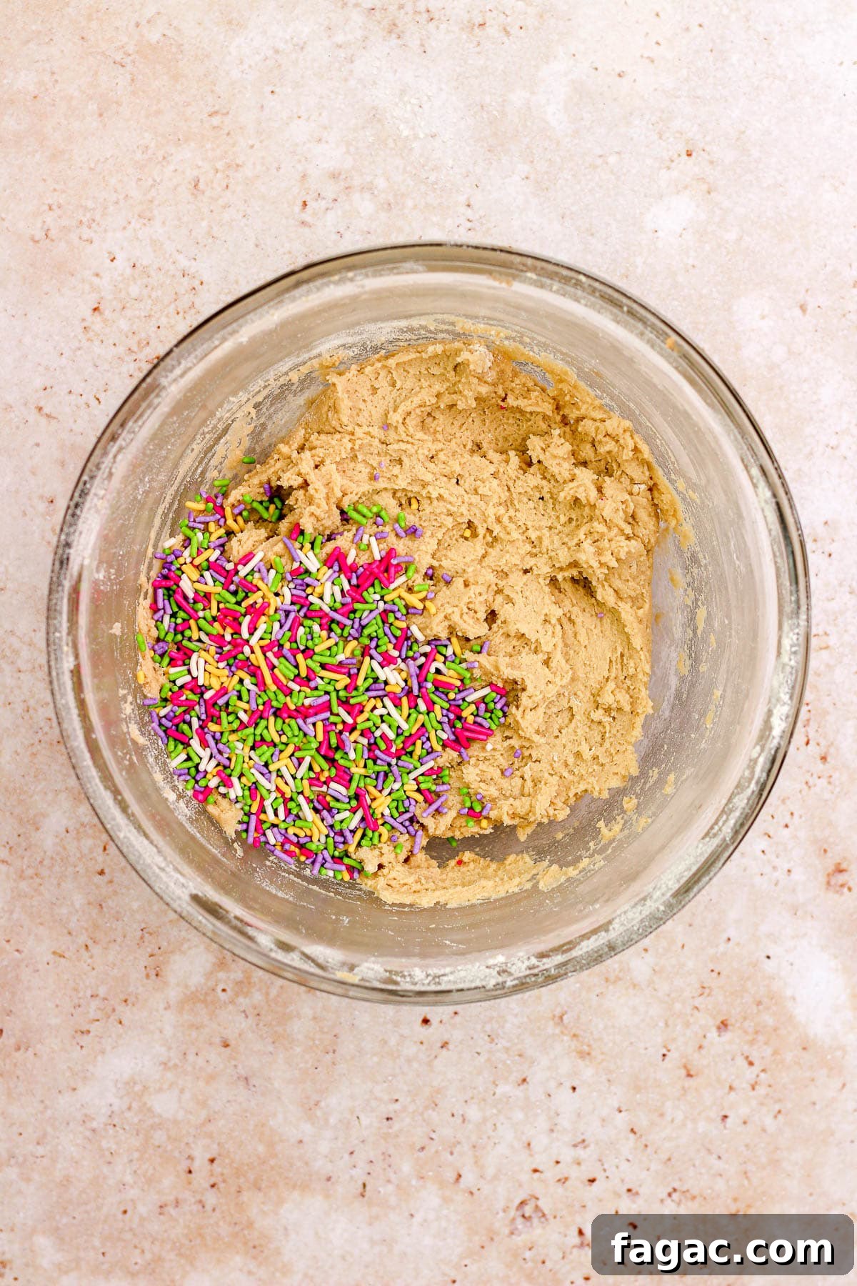 A glass bowl filled with sprinkle sugar cookie dough.