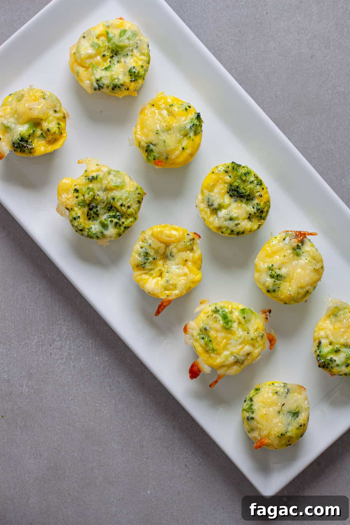 Broccoli Cheddar Mini Egg Bites: Protein-Packed Breakfast Bites 10 A tray of mini broccoli and cheddar egg bites on a gray table.