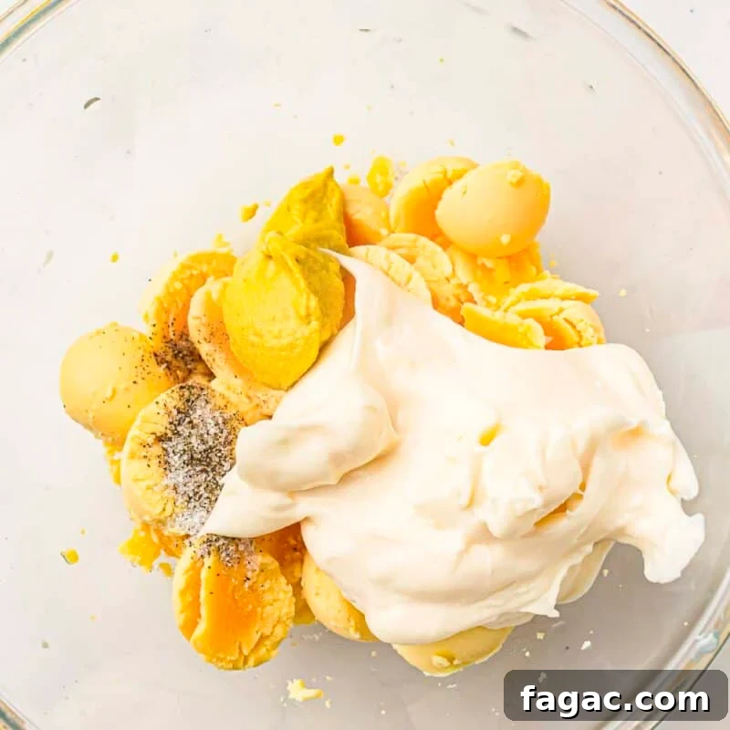 Process step 3 - remove the yolks and place them in a bowl. Mix with mayonnaise, mustard, vinegar, salt, and pepper until smooth.
