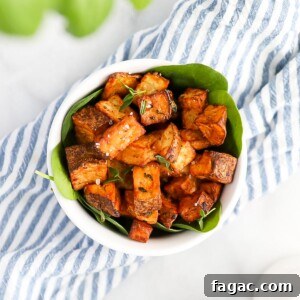 An overhead shot of crispy diced potatoes, garnished with salt and fresh herbs.