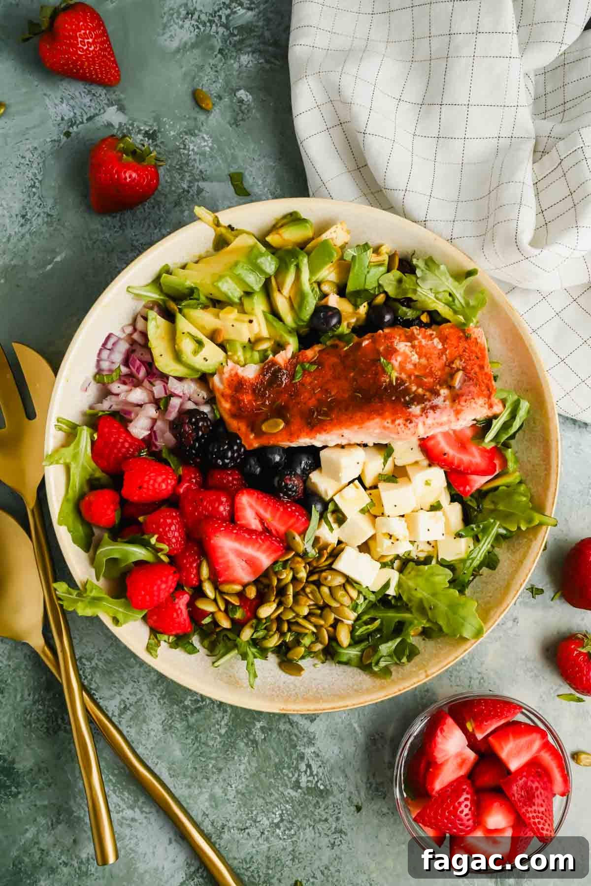 salad with berries, avocado, cheese and pumpkin seeds topped with broiled salmon.