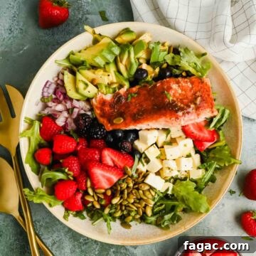 salad with berries, avocado, cheese and pumpkin seeds topped with broiled salmon.