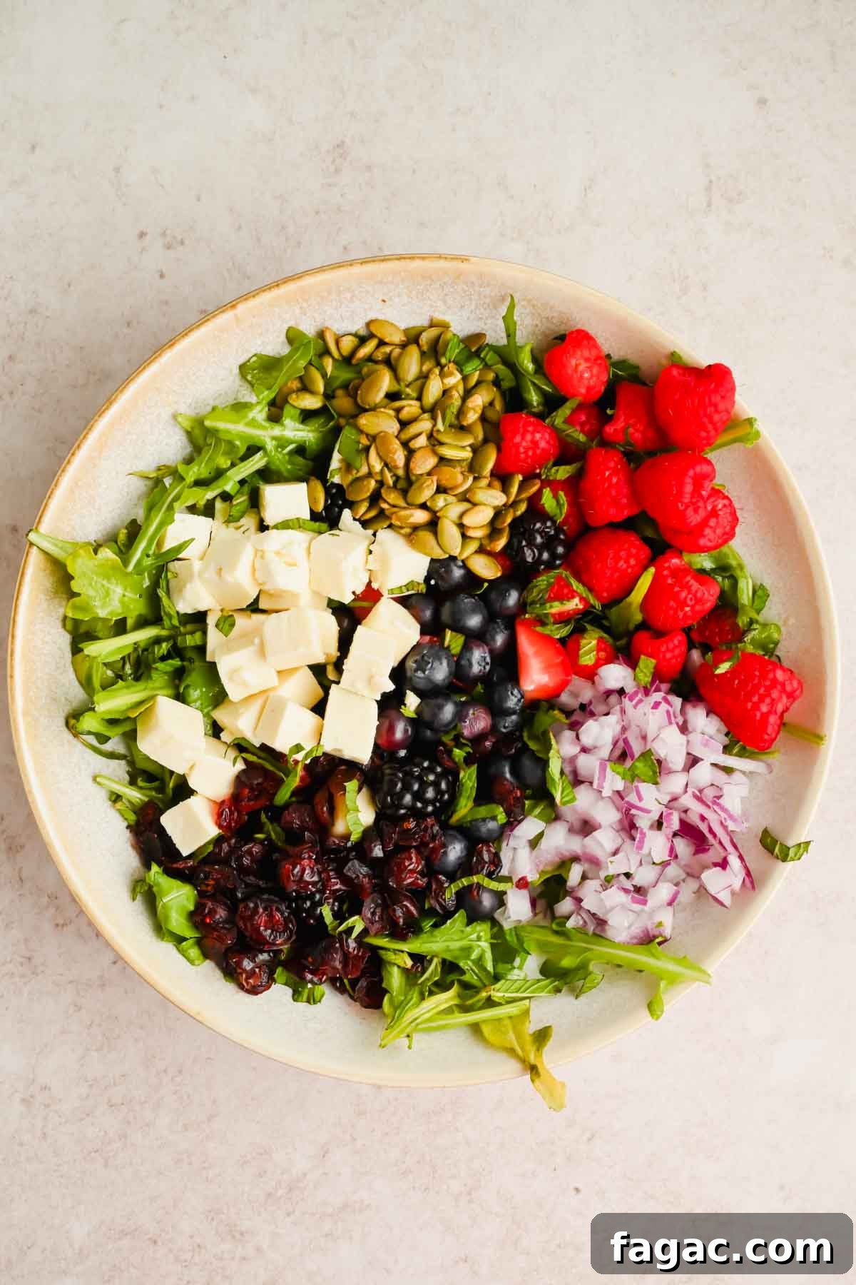 salad with berries, avocado, cheese and pumpkin seeds topped with broiled salmon.