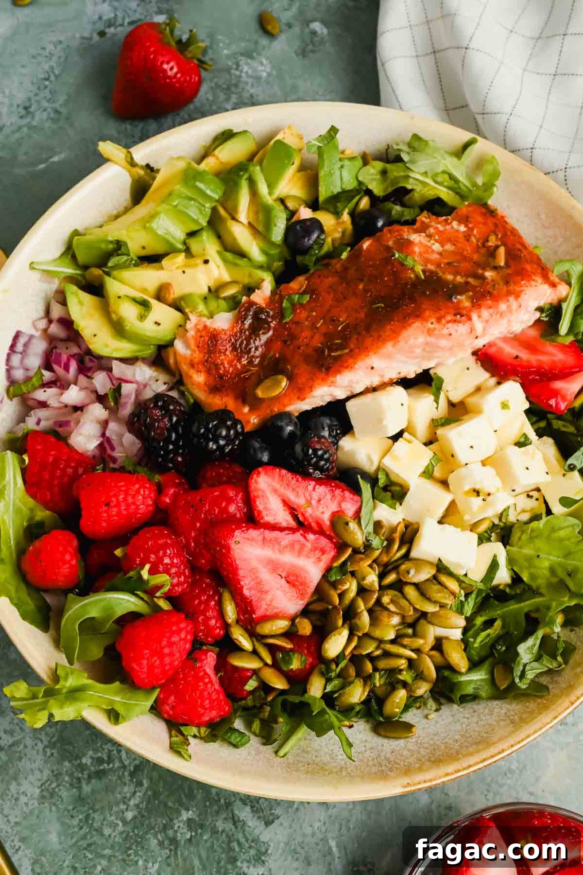 salad with berries, avocado, cheese and pumpkin seeds topped with broiled salmon.