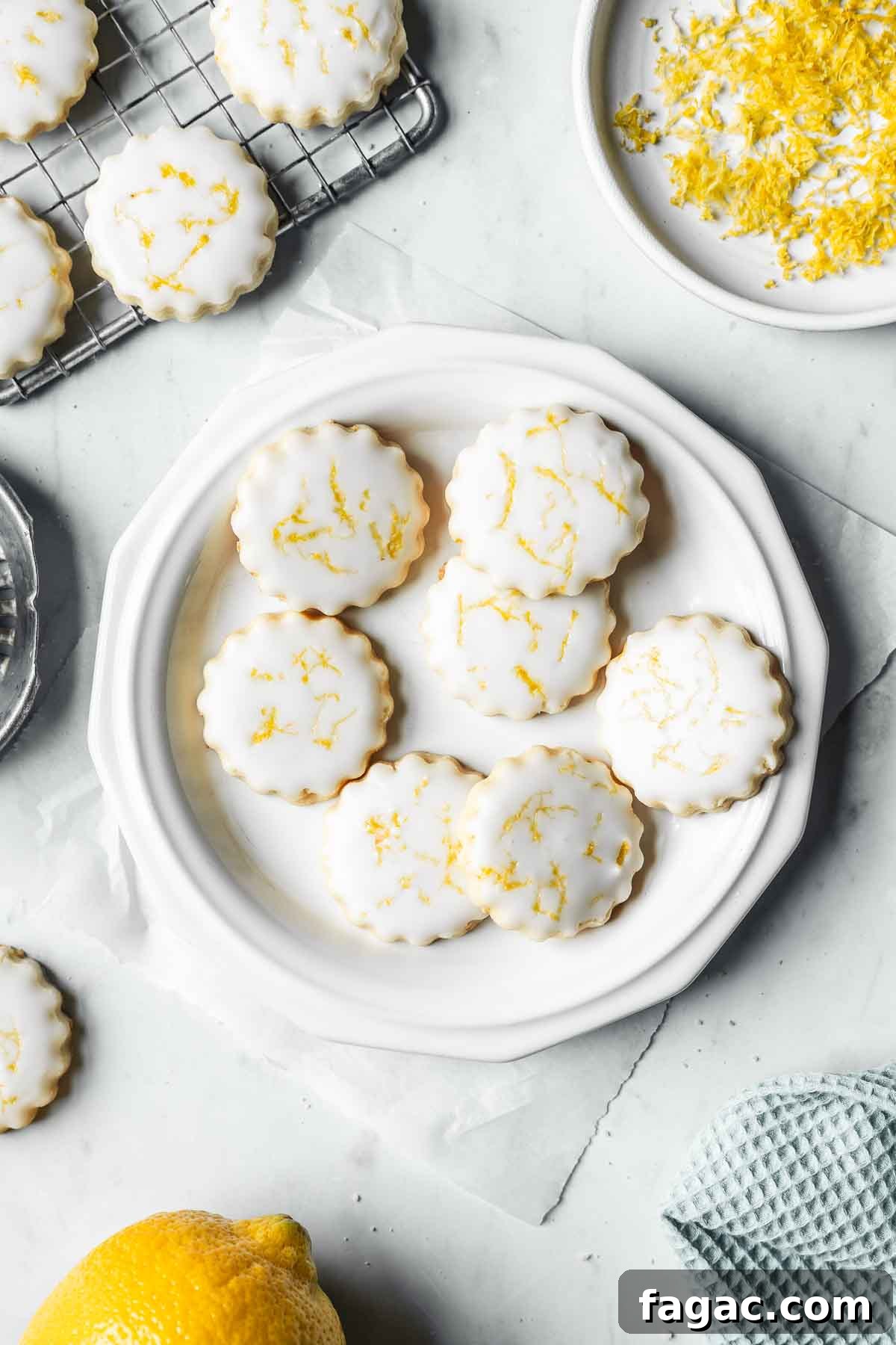 Glazed shortbread on a white plate with lemon zest nearby.