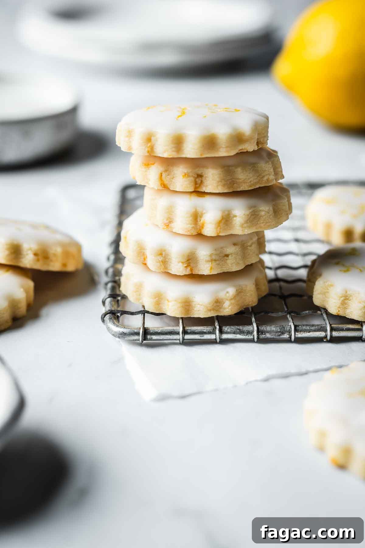 A stack of glazed lemon shortbread cookies on a cooling rack.