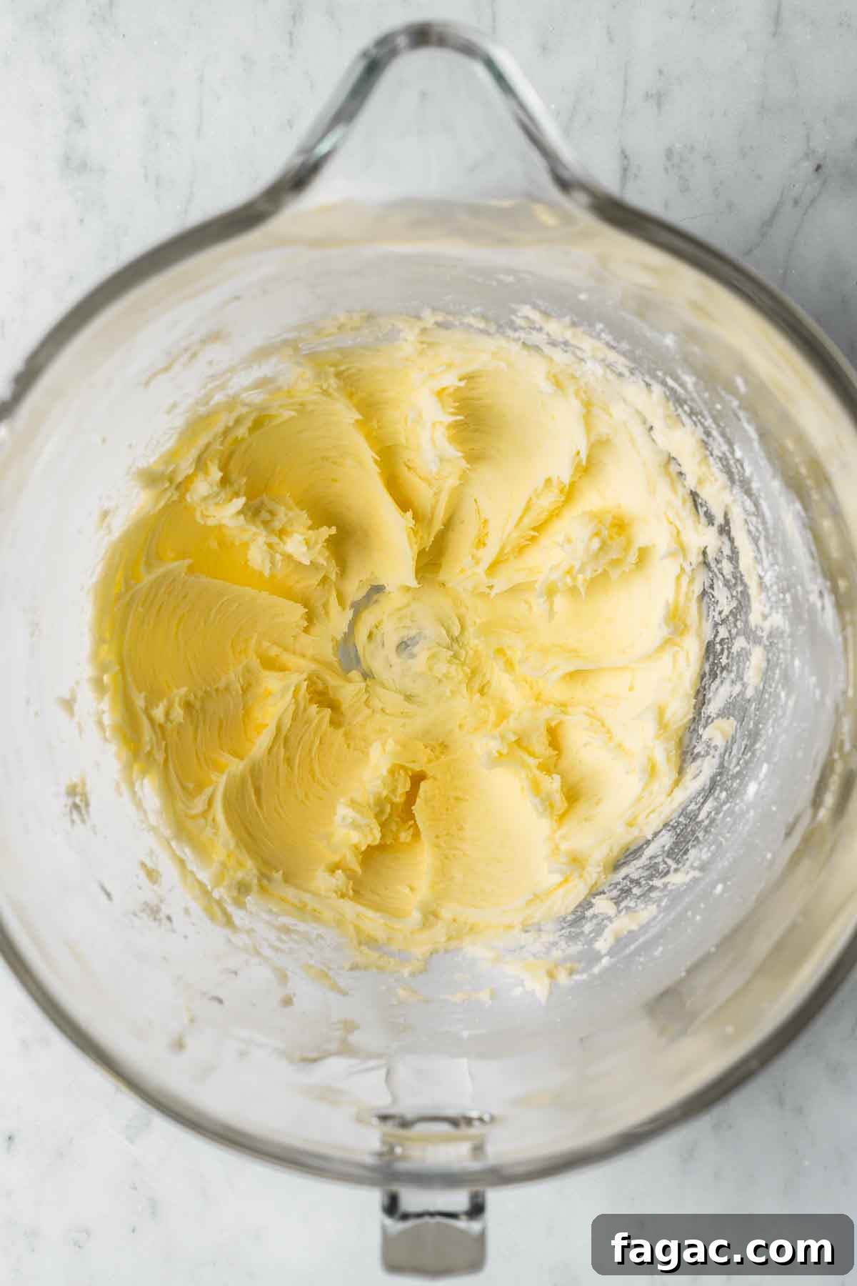 Creamed butter in a clear glass mixing bowl.