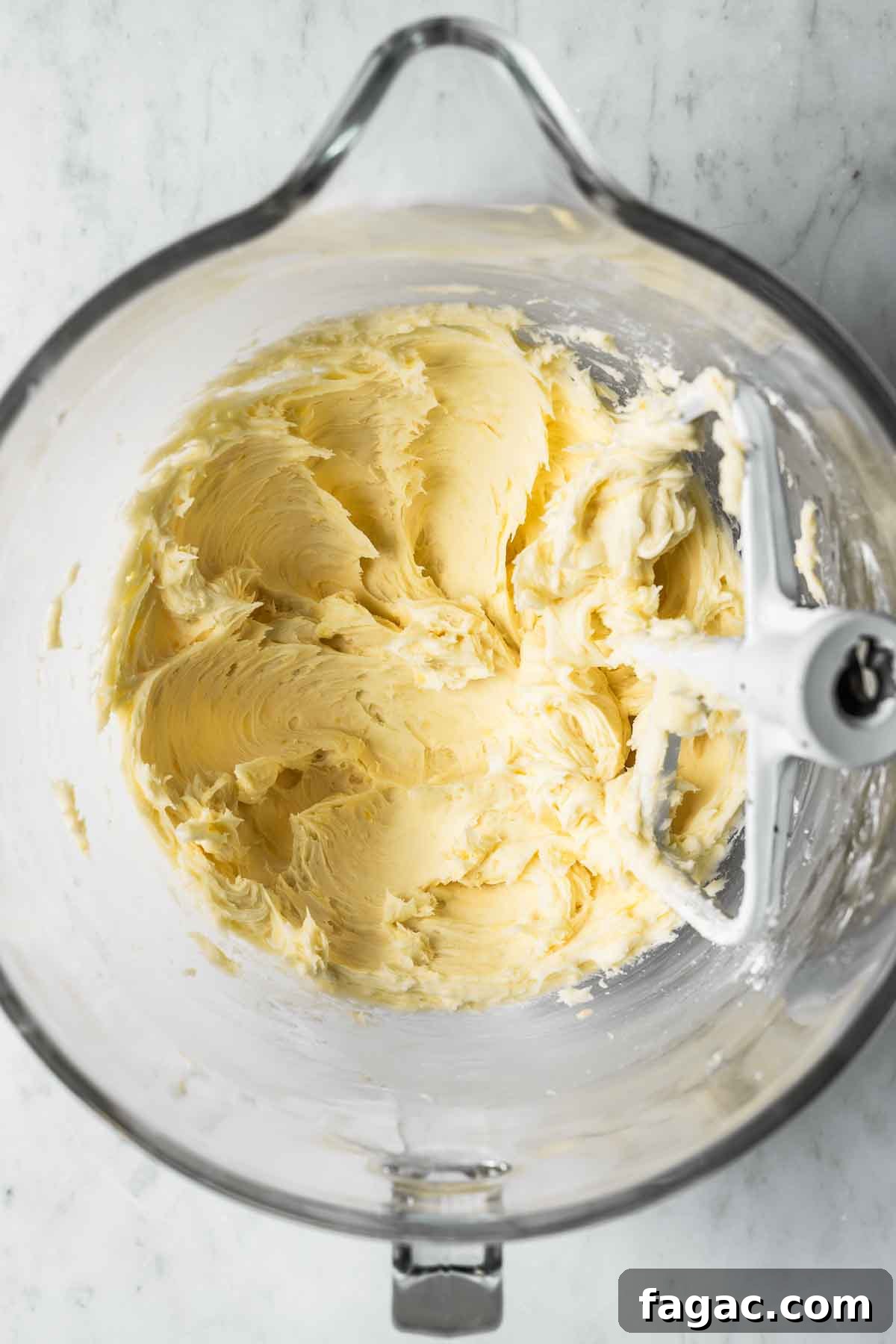 Creamed butter and sugar in a clear glass mixing bowl.