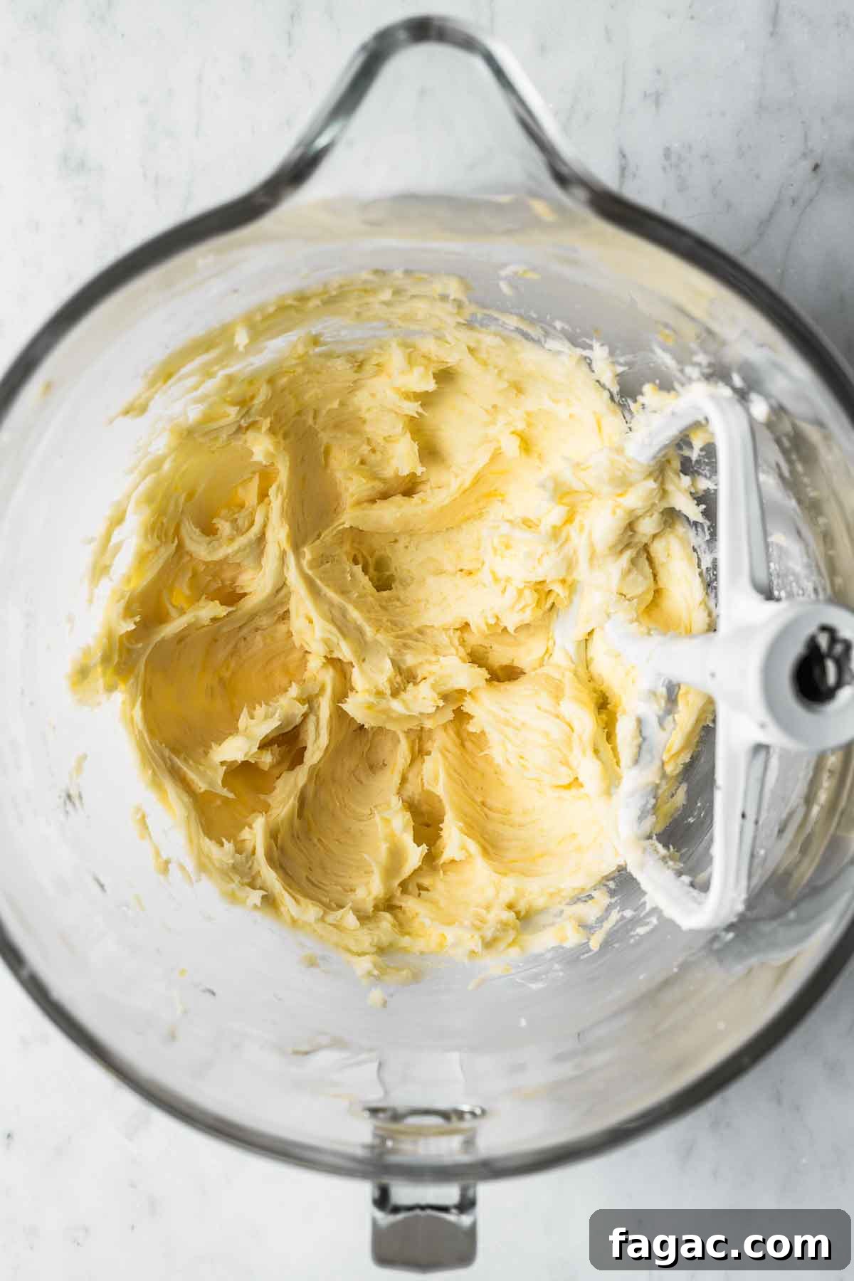 Butter, sugar, lemon oil and lemon zest mixed together in a glass mixing bowl.