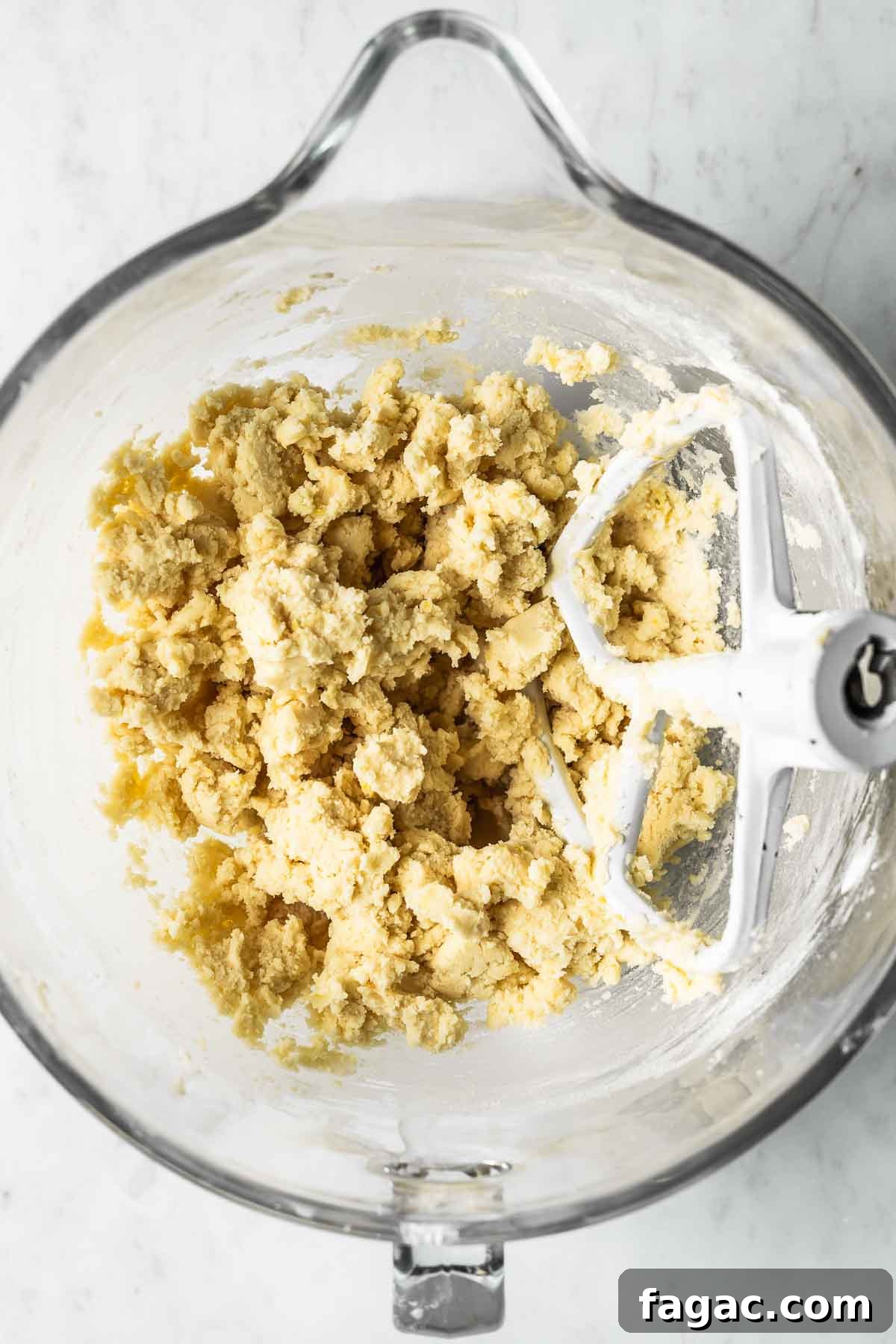 Dough for shortbread cookies in a clear glass mixing bowl.