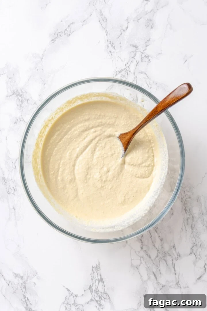 Make the ricotta layer. RIcotta mixture in glass bowl with wooden spoon.