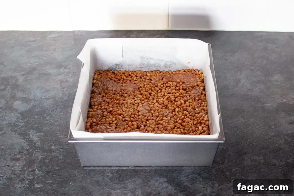 Quick Mars Bar Slice Recipe — No-Bake Chocolate Treat 7 Mars Bar and Rice Krispie mixture pressed into a lined square baking tin.