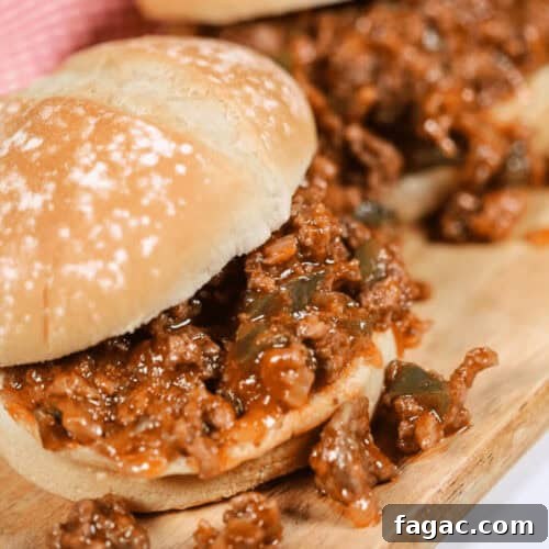 Two delicious Wimpies, also known as Easy Sloppy Joes, filled with a savory mixture of ground meat, onions, and green peppers on a wooden board.