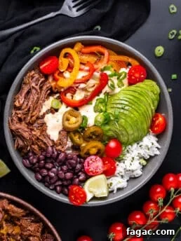 overhead view of a bowl with shredded beef, black beans, sautéed veggies, avocado and cilantro lime rice