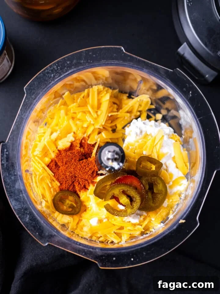 food processor bowl with cottage cheese, grated sharp cheddar, taco seasoning and pickled jalapenos
