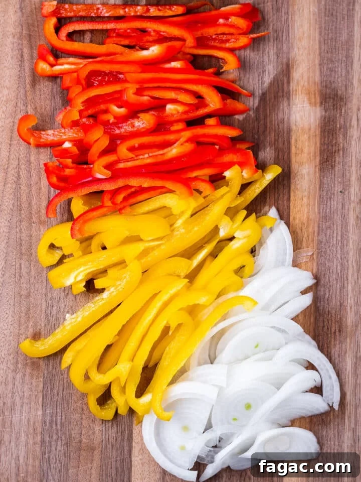 wood cutting board with sliced bell peppers and onions