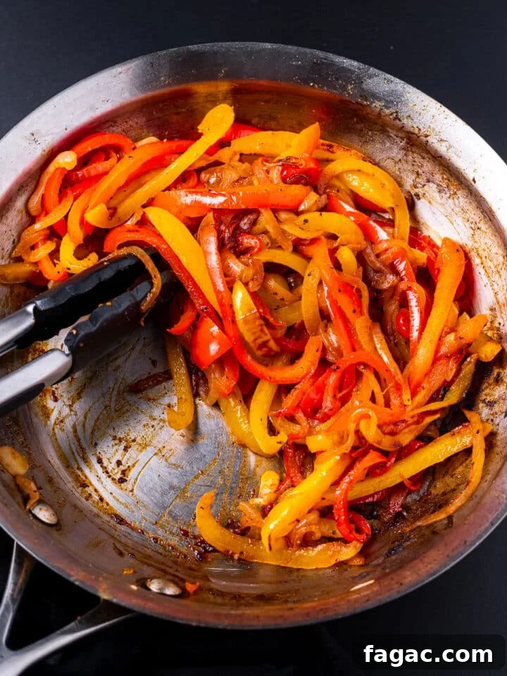 sauteed bell peppers and onions in a stainless steel skillet