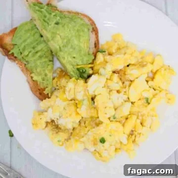 Dairy-free scrambled eggs on a white plate with avocado toast beside them.