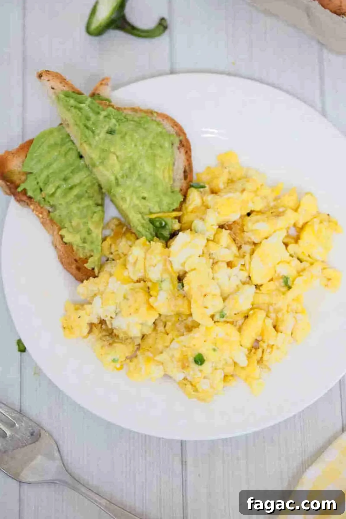 Dairy-free scrambled eggs on a white plate with avocado toast beside them.