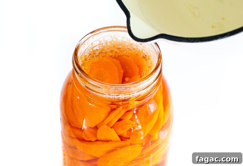 Quick Homemade Pickled Carrots: Crisp, Tangy Recipe for Jars 7 pouring brining liquid on top of sliced carrots in mason jar