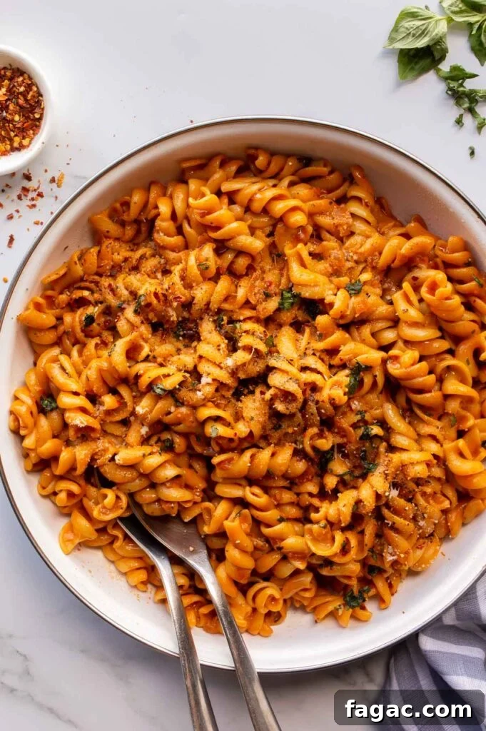 20-Minute Creamy Vegan Tomato Pasta Recipe 9 A white ceramic pan with pasta in an orange creamy sauce.