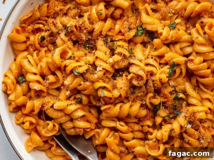 white pan with orange saucy pasta on a white background.