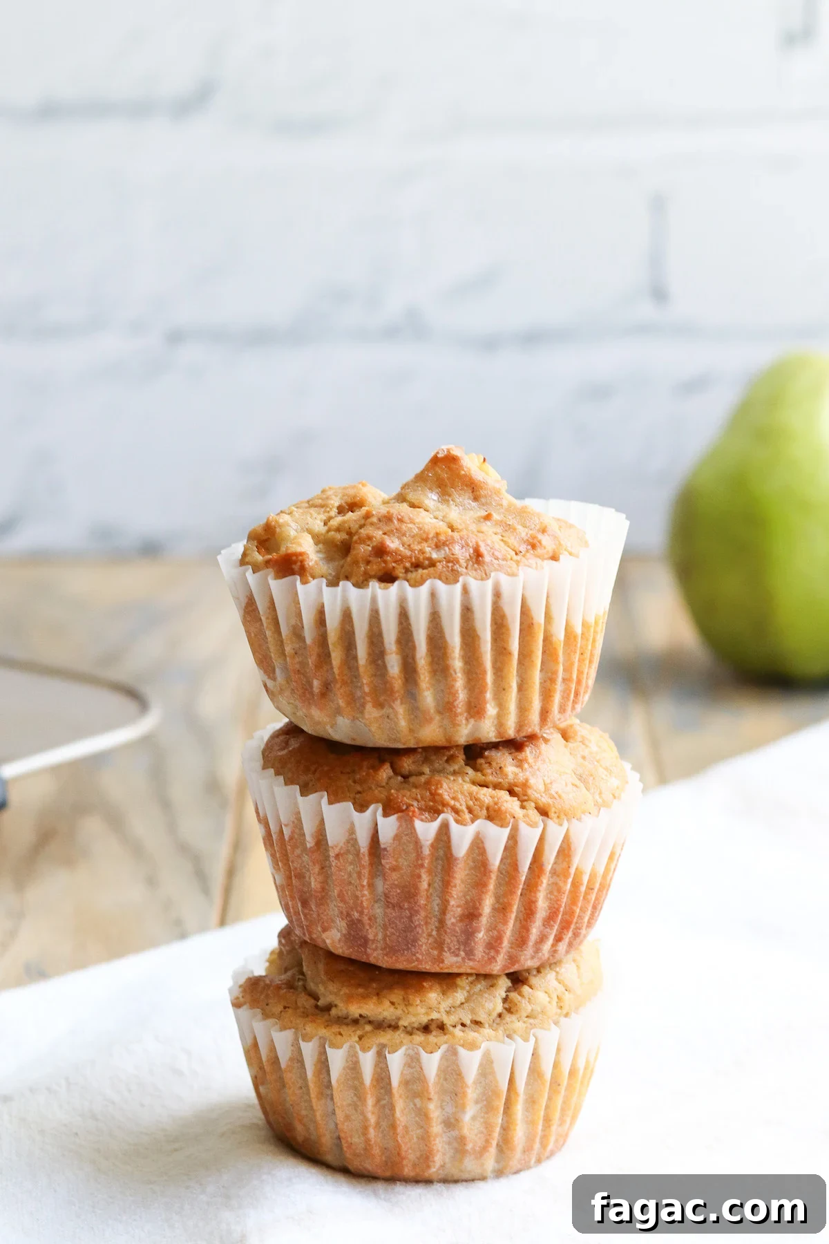 A stack of 3 baked pear muffins. 