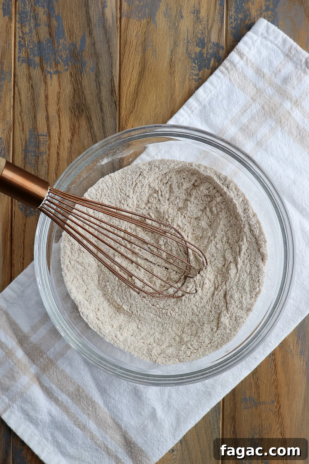 Dry ingredients for pear muffins whisked together in a glass bowl.