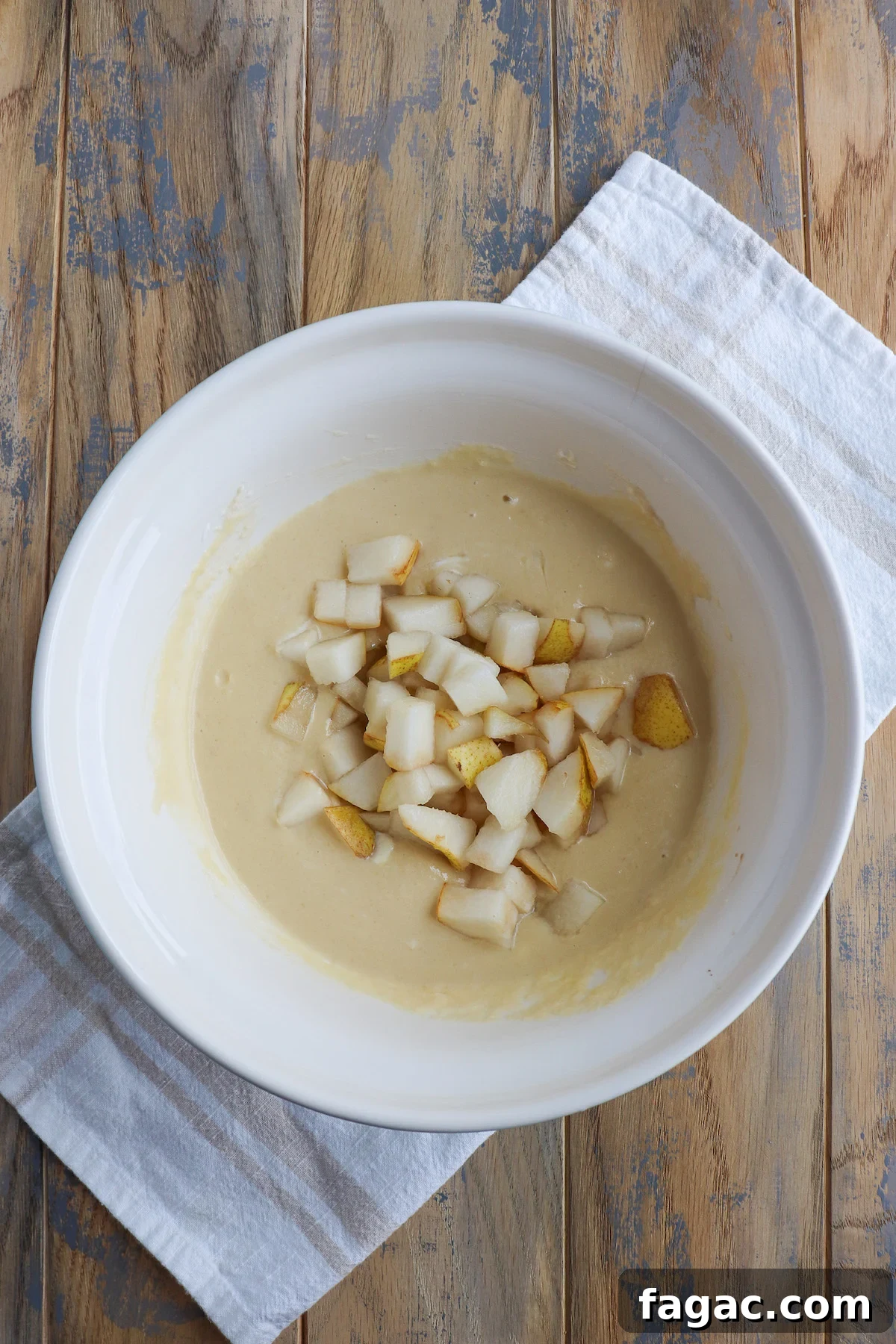 Wet ingredients with diced pears in a mixing bowl. 
