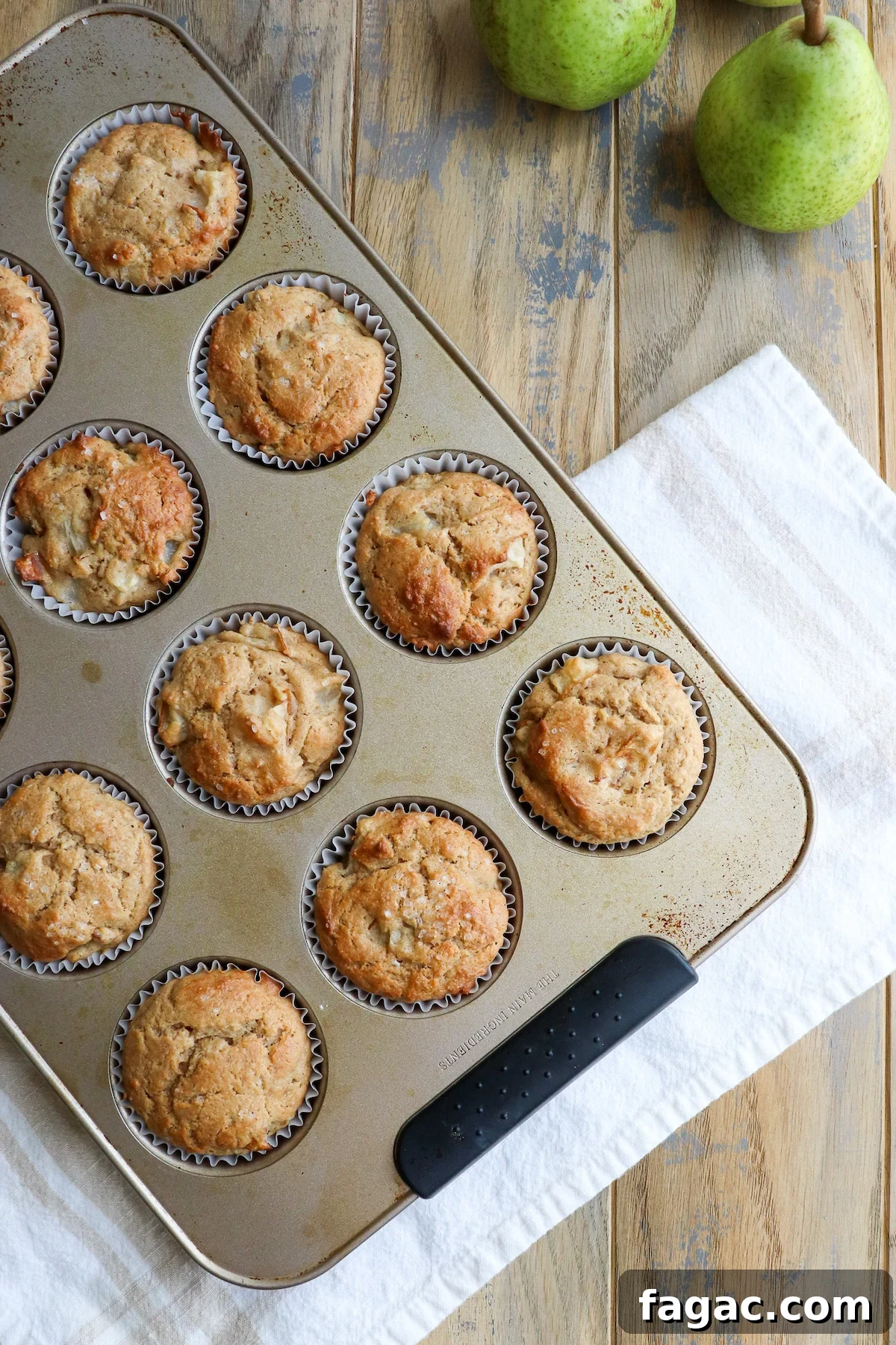 Baked golden brown pear and sour cream muffins in muffin tin.