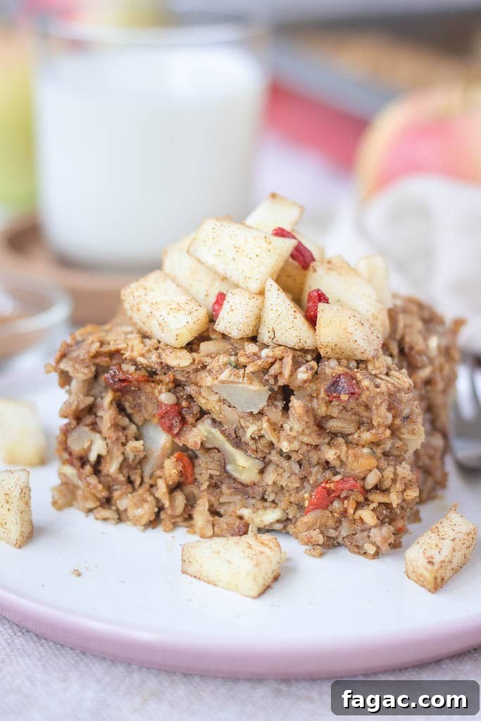 Apple Cinnamon Baked Oatmeal Recipe for Warm Fall Breakfast 2 Slice of apple cinnamon baked oatmeal topped with slices of fresh apples served on a plate