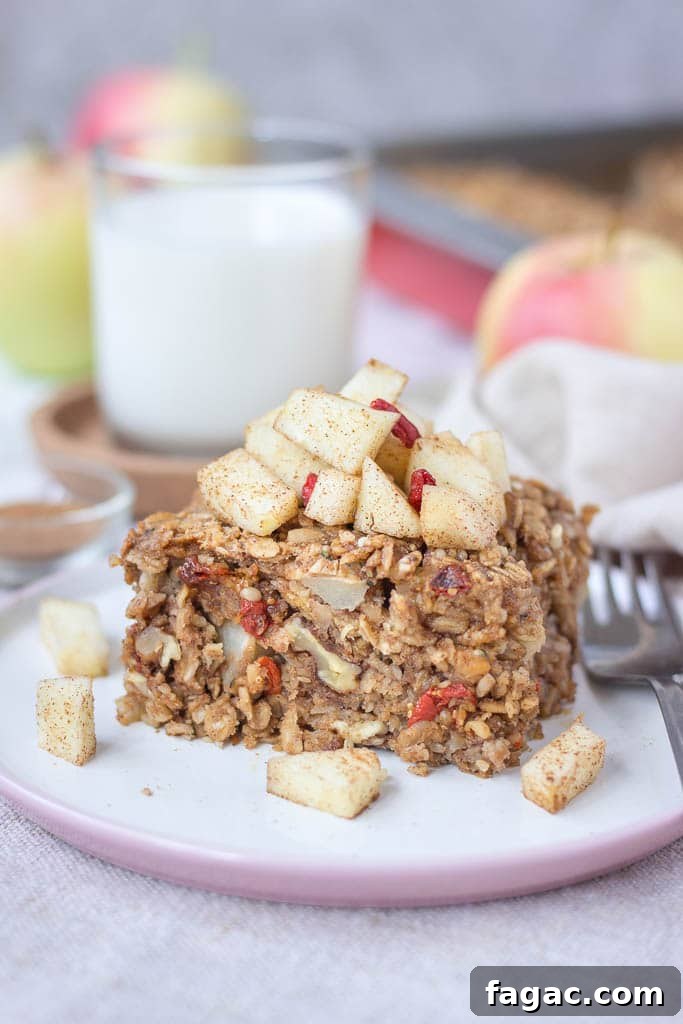 Apple Cinnamon Baked Oatmeal Recipe for Warm Fall Breakfast 4 Slice of apple cinnamon baked oatmeal topped with slices of fresh apples served on a plate