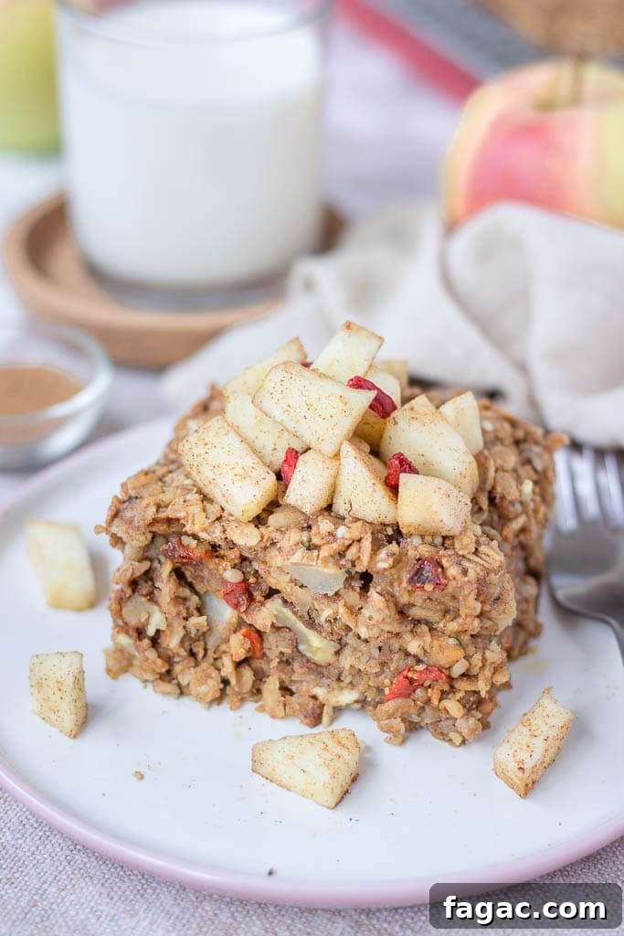 Apple Cinnamon Baked Oatmeal Recipe for Warm Fall Breakfast 5 Slice of apple cinnamon baked oatmeal topped with slices of fresh apples served on a plate