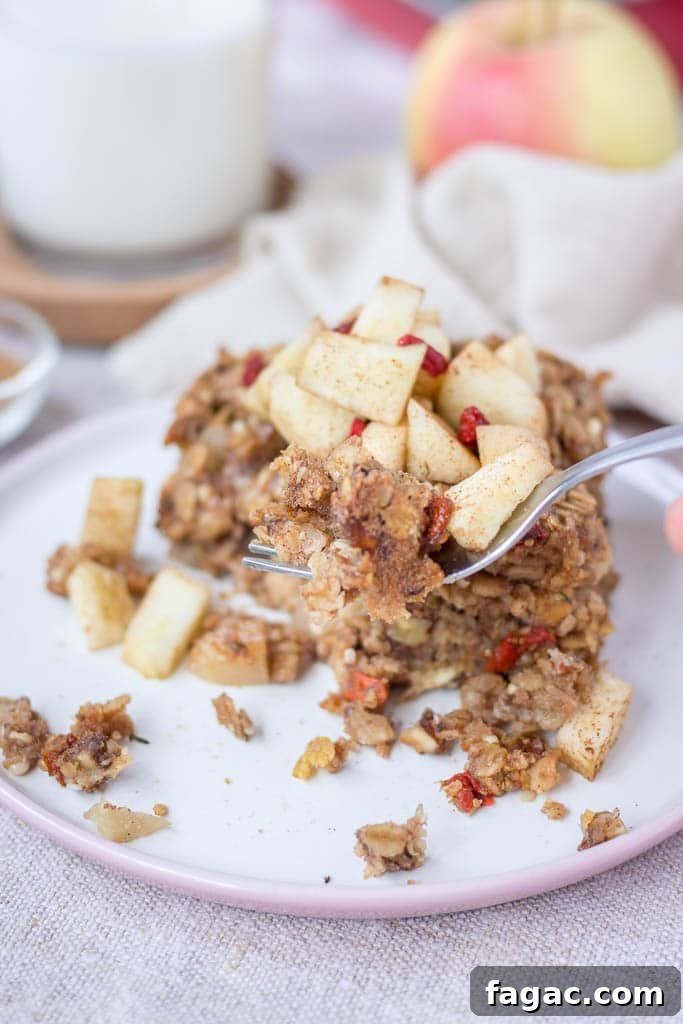 Apple Cinnamon Baked Oatmeal Recipe for Warm Fall Breakfast 6 Slice of apple cinnamon baked oatmeal topped with slices of fresh apples served on a plate