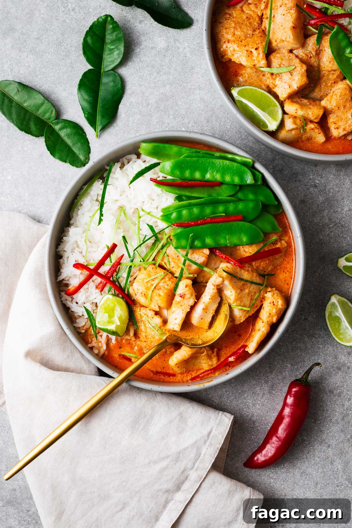 Thai Red Curry Paste Substitutes: What to Use and What to Avoid 10 A bowl with steamed jasmine rice, Thai fish red curry and snow peas topped with sliced red chile and kaffir lime leaves wit a golden serving spoon.